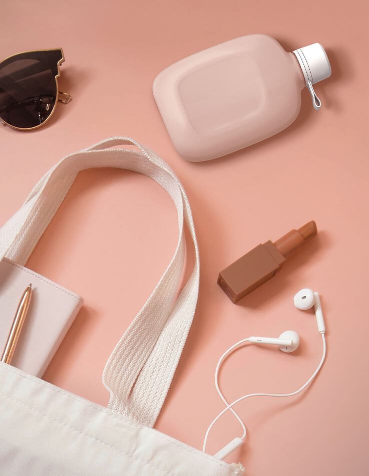 Pinkes mobiles Bidet Purpo mit zusätzlichen Gegenständen wie Lippenstift, Kopfhörern oder Tasche.