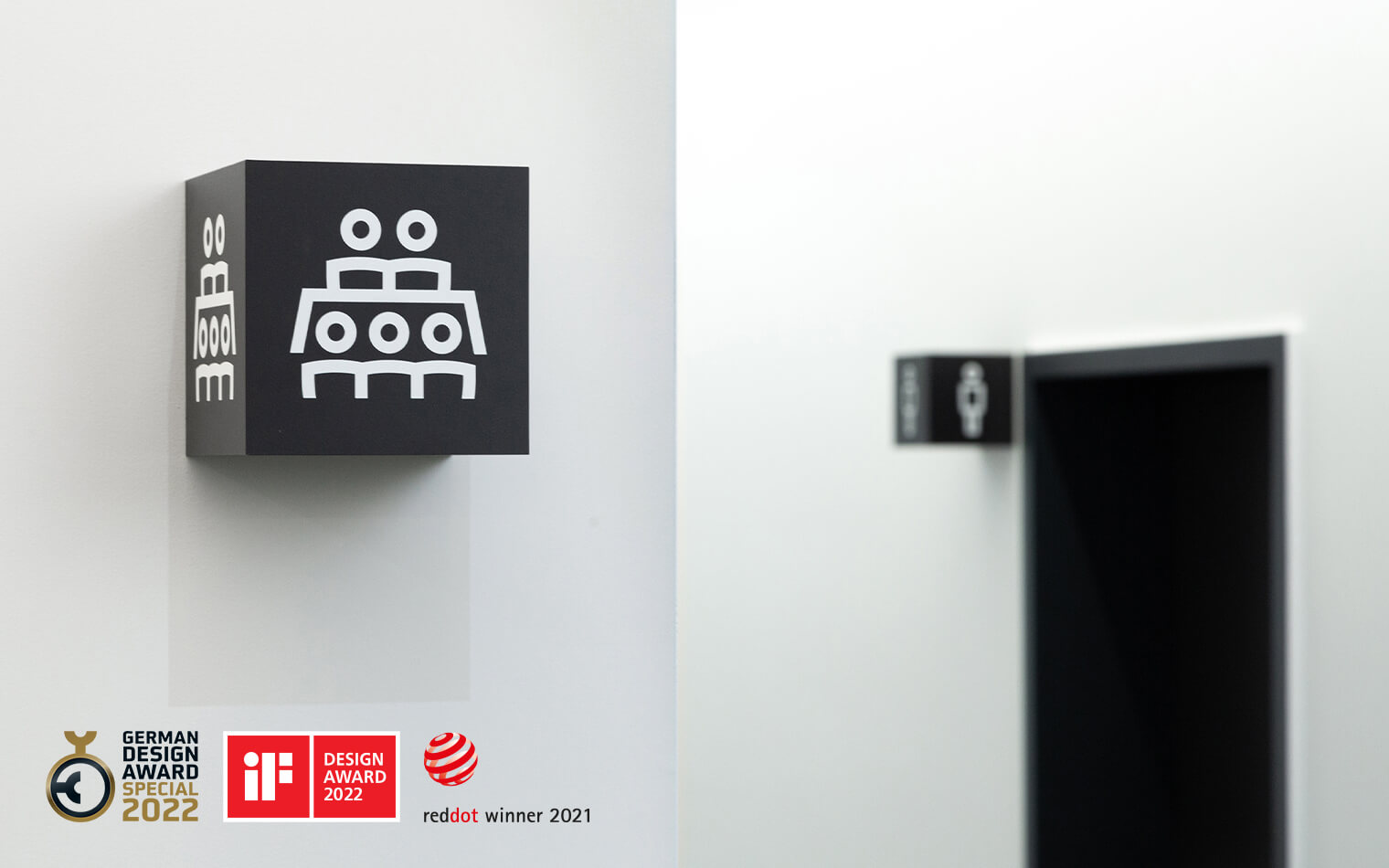 Auf diesem Bild sind ein Element der Wilo Signaletik und die Logos German Design Award 2022, Red Dot Winner 2021 und iF Design Award 2022 zu sehen.