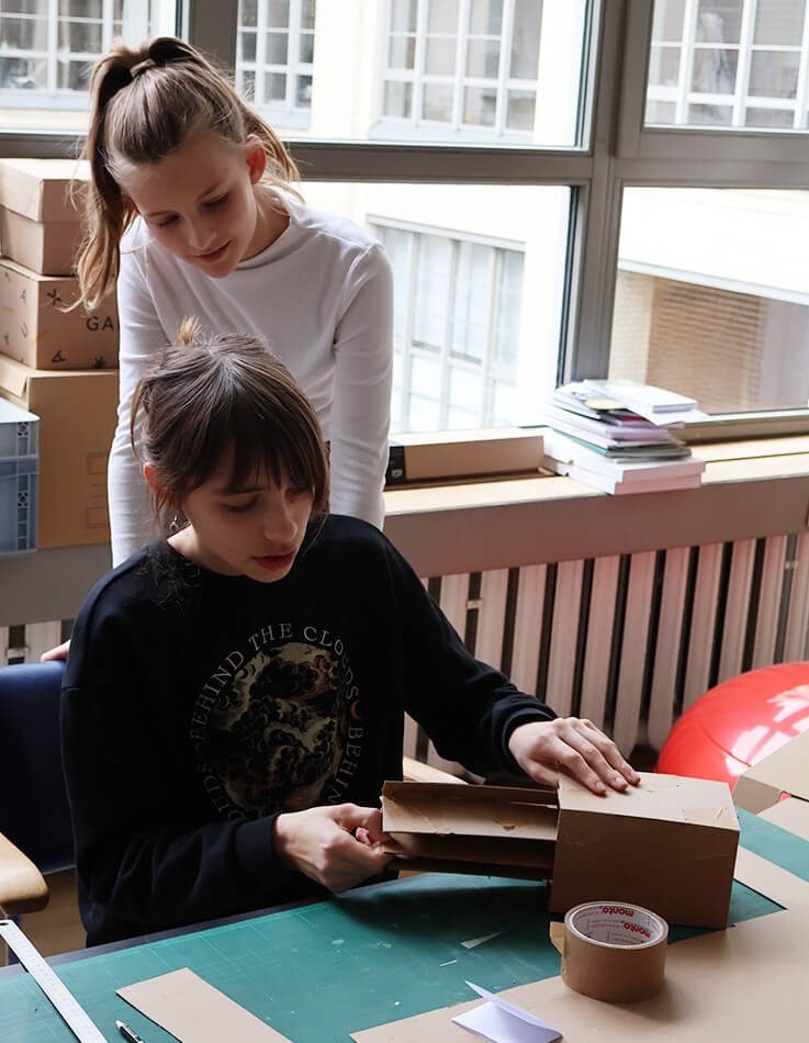 Lara-Marie and Emma building models out of corrugated cardboard.